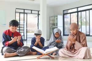 Portrait of muslim kids praying with holy Quran
