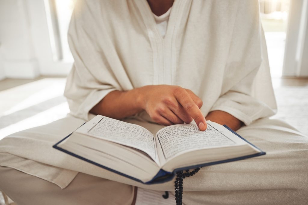 Reading book, muslim or hands of man with Quran on Eid Mubarak praying to God or worship at home. A