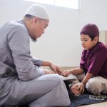Side View Of Muslim Father Teaching Son How To Reading Quran At Home