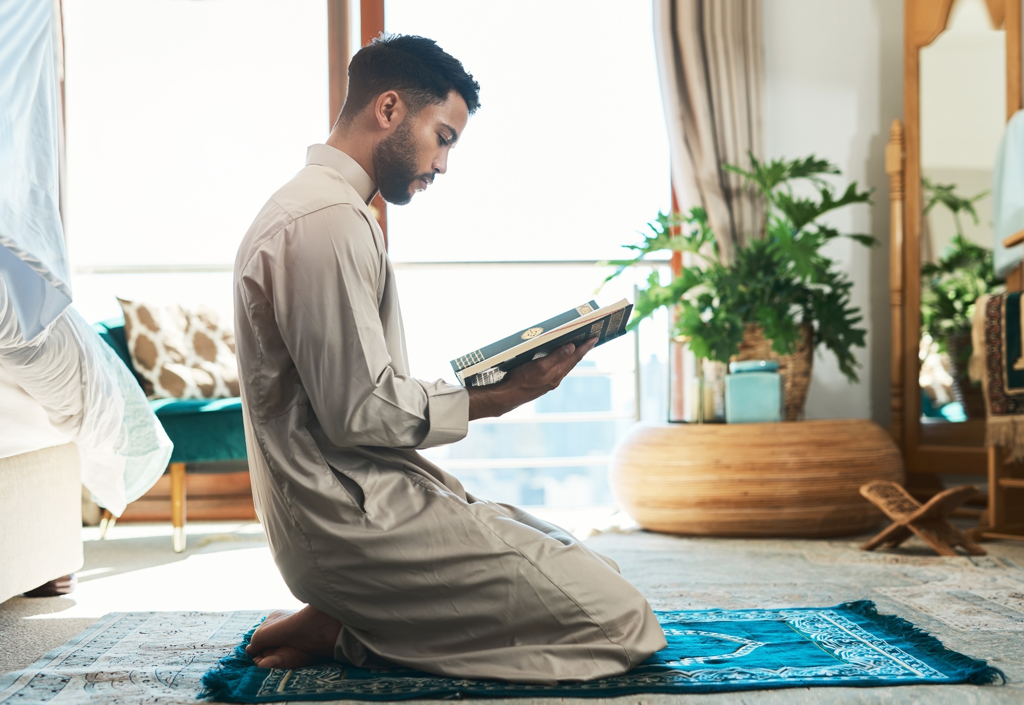 This is how I fight my battles. Shot of a young muslim man reading in the lounge at home.